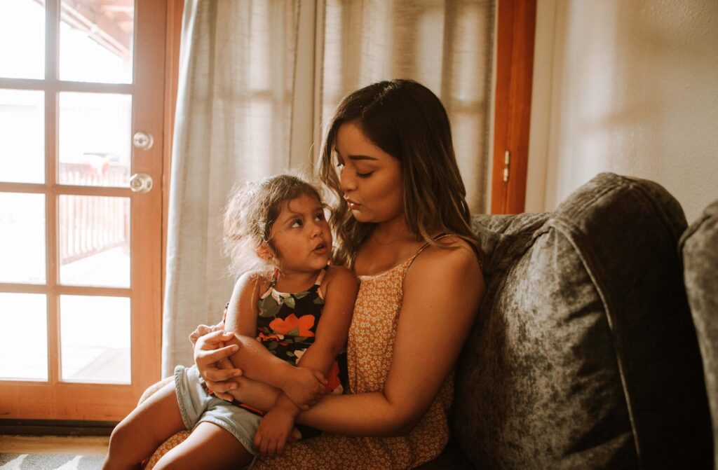 Minnesota mom in red and black floral tank top sitting on gray sofa who seeked housing and shelter